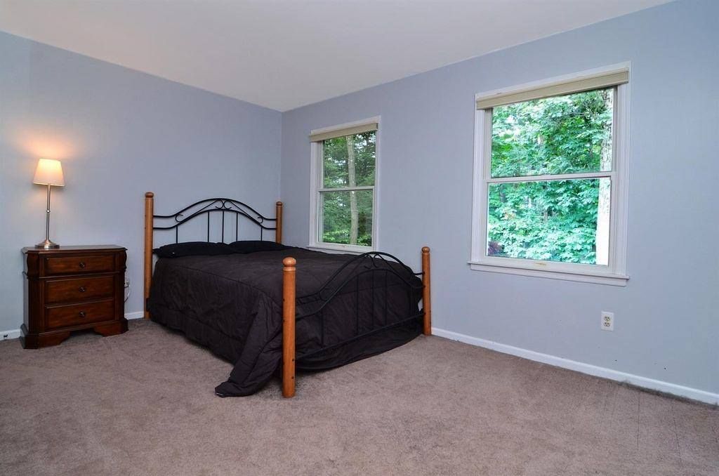 A Bedroom With A Bed Dresser And Two Windows
