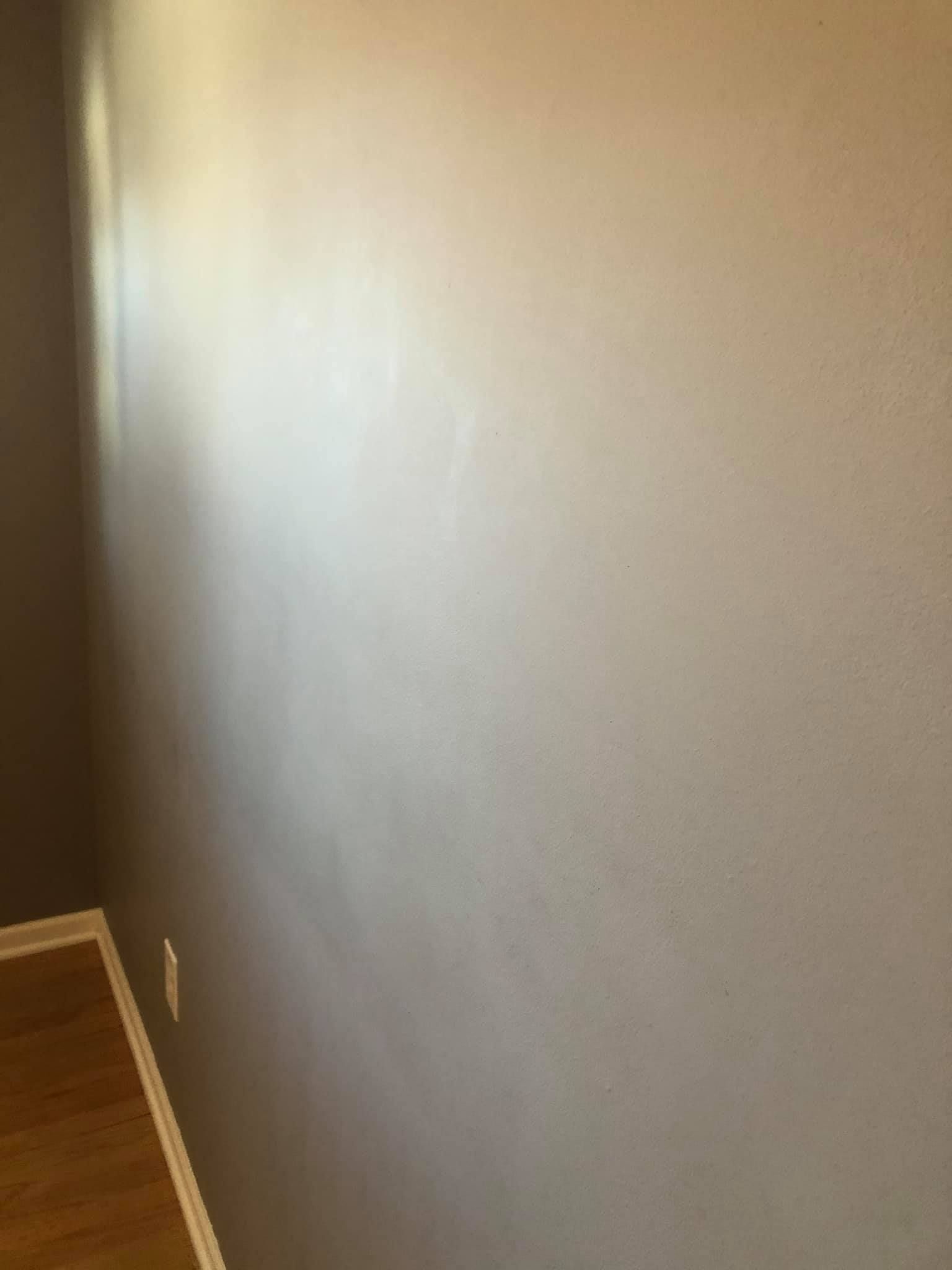 A room with a gray wall and a wooden floor.