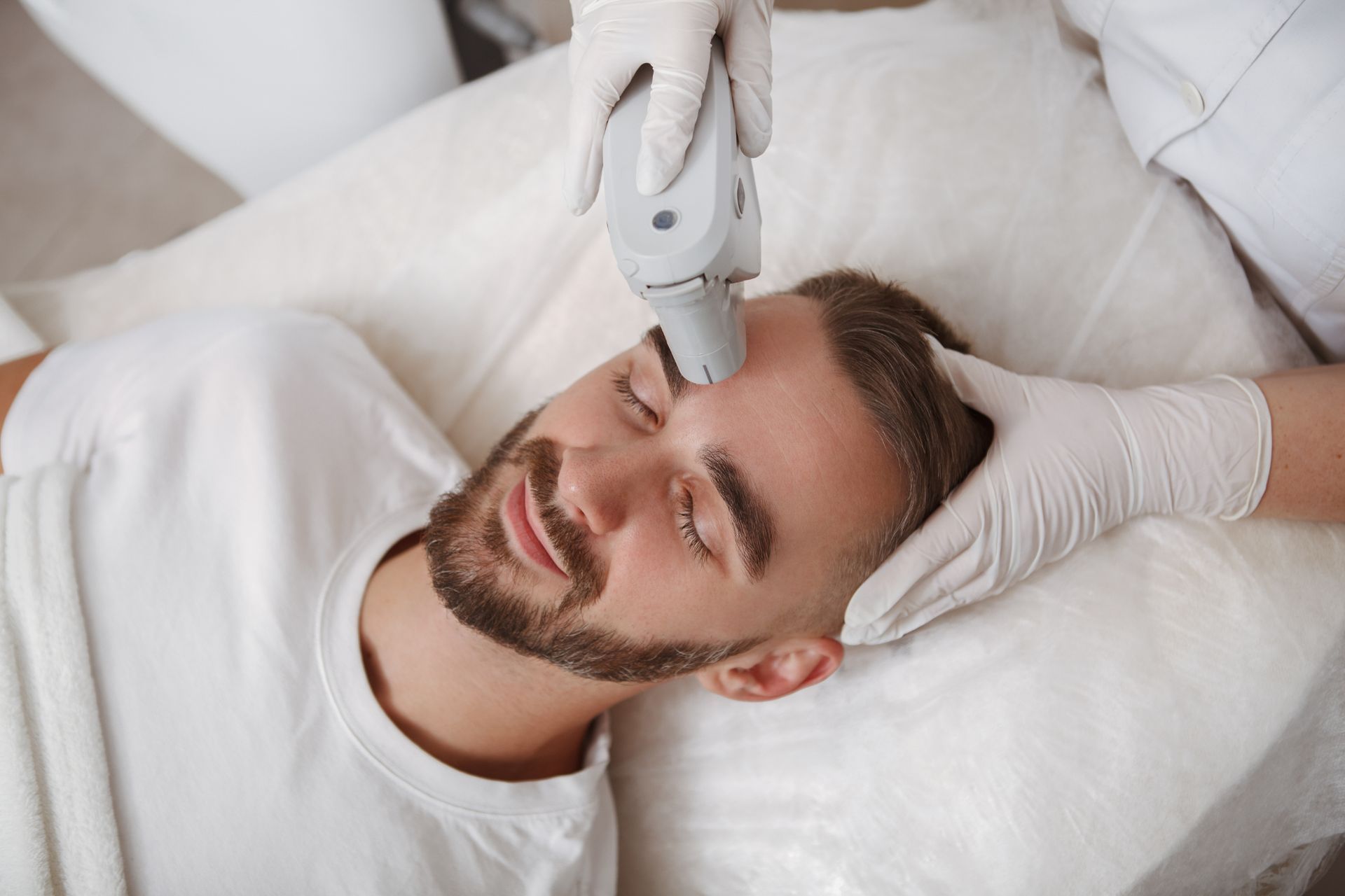 closeup of dermatologist using laser device on a man's forehead for skin rejuvenation