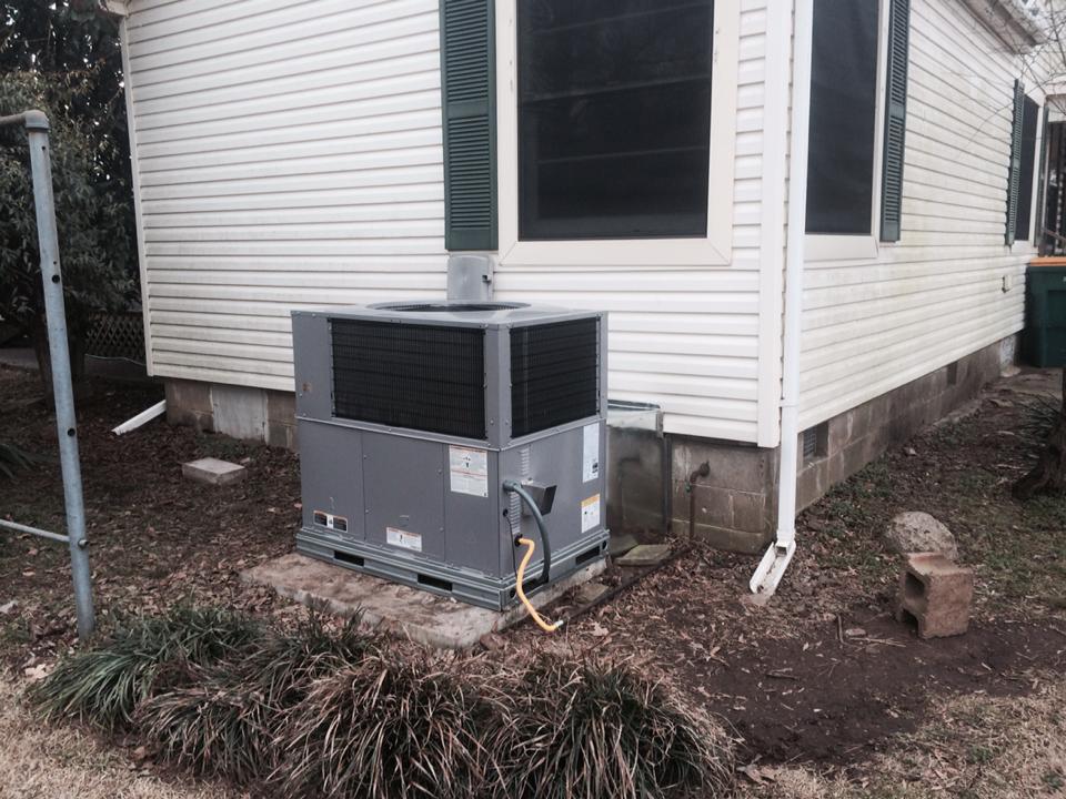 A large air conditioner is sitting on the side of a house.