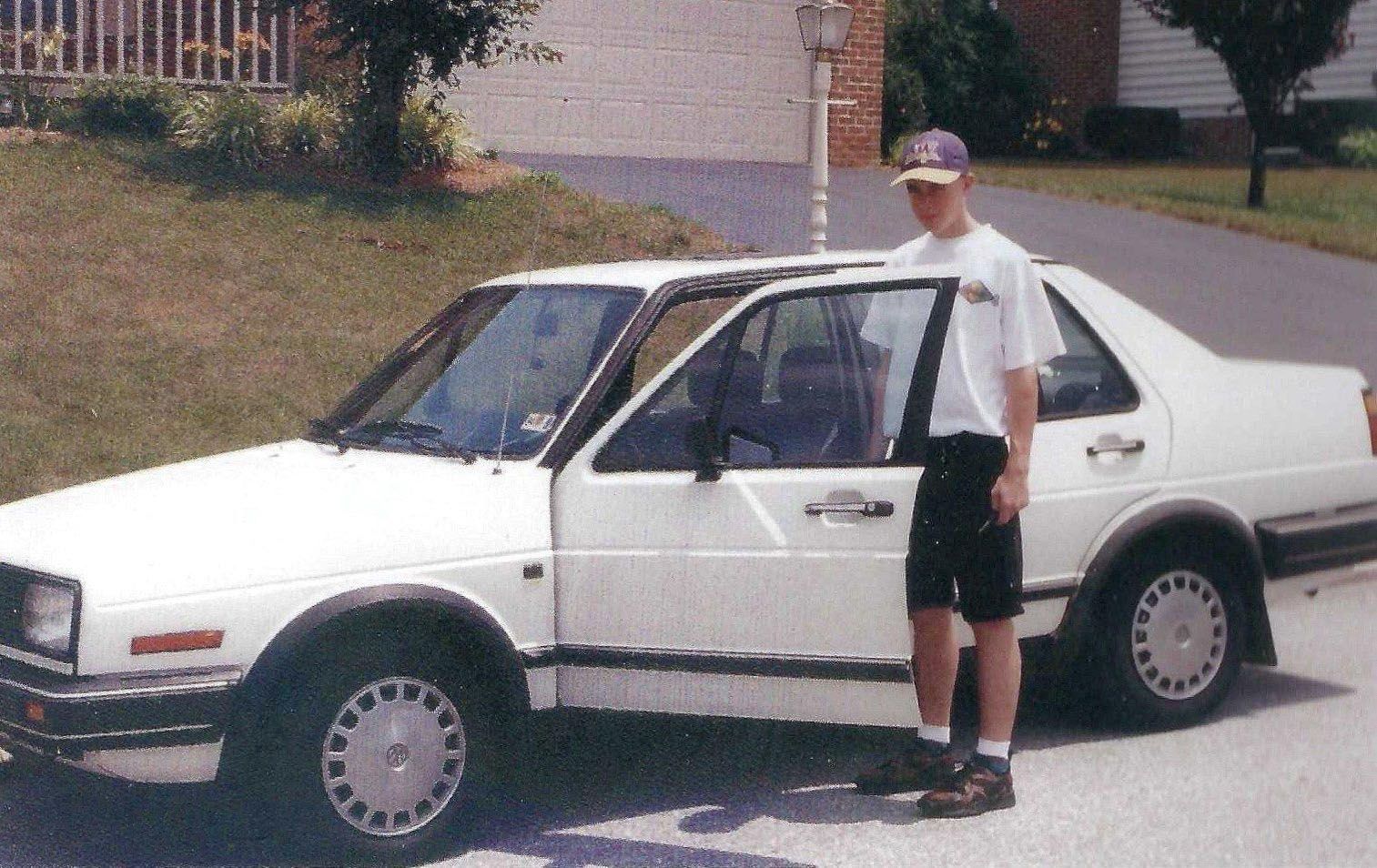 A man standing next to a white car with the door open