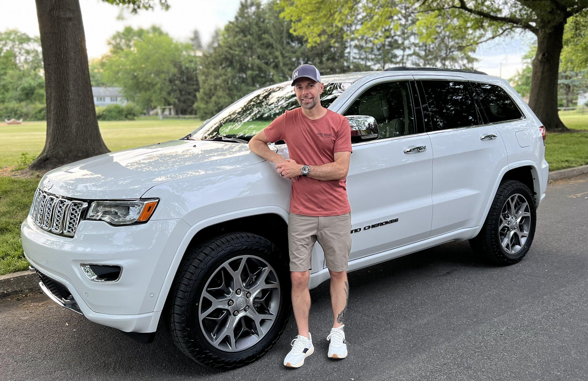 A man is standing in front of a white jeep grand cherokee.