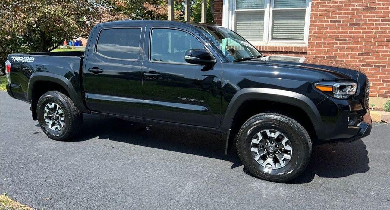 A black truck is parked in front of a brick house.