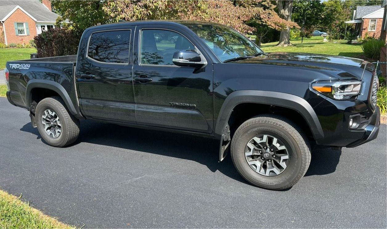 A black toyota tacoma truck is parked in a driveway.