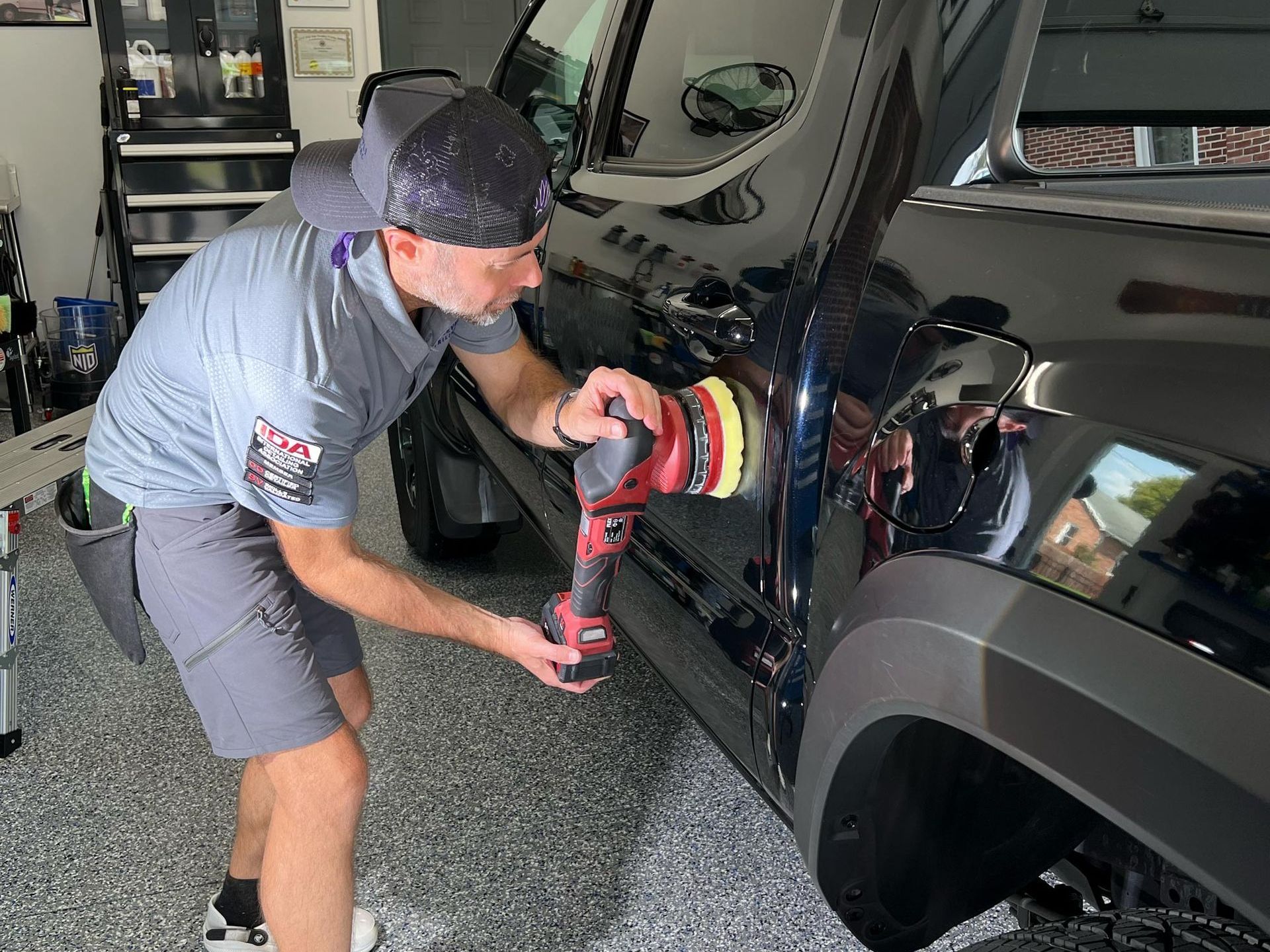 A man is cleaning the windshield of a car in a garage.