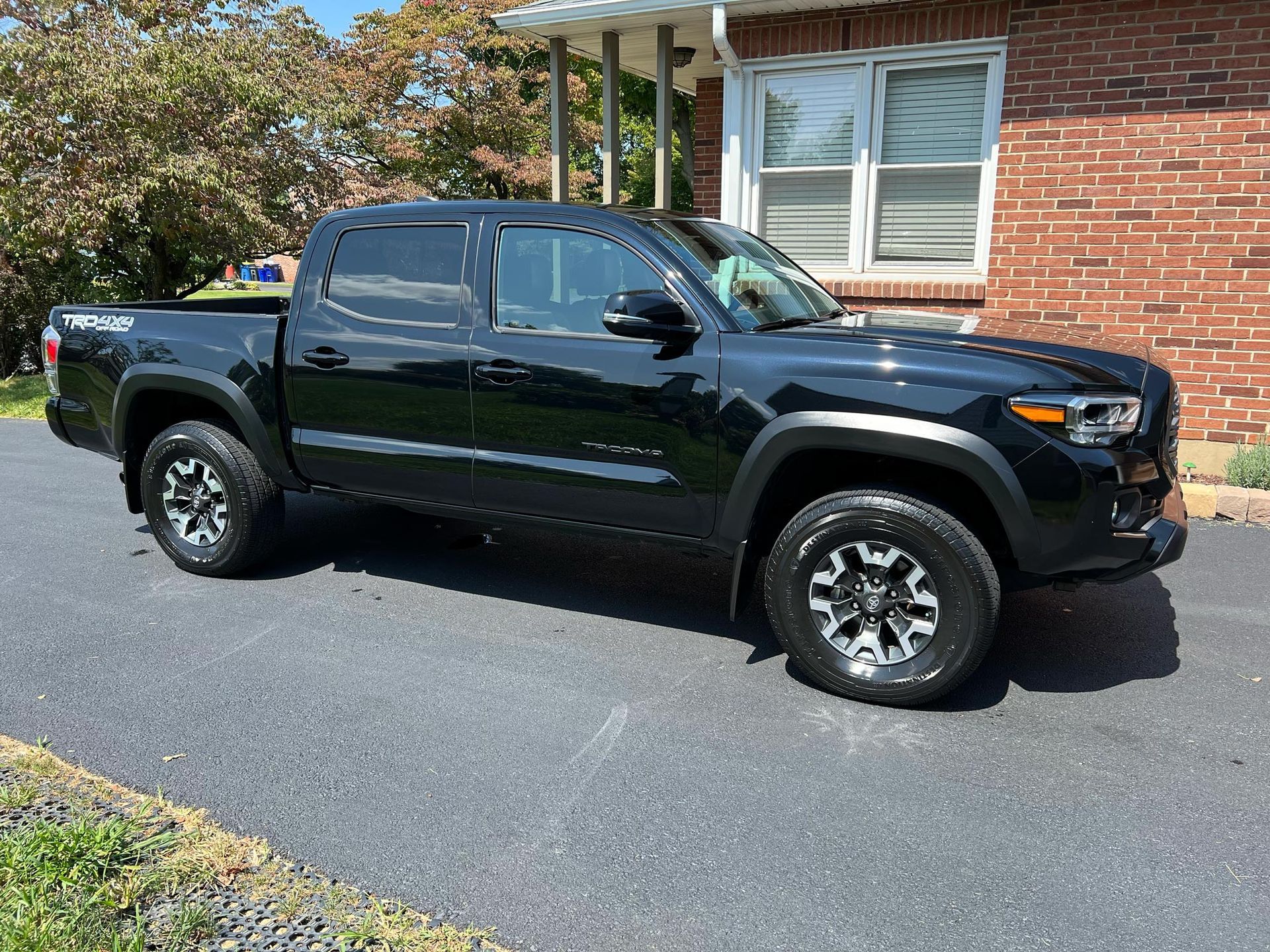 A black truck is parked in front of a brick house.