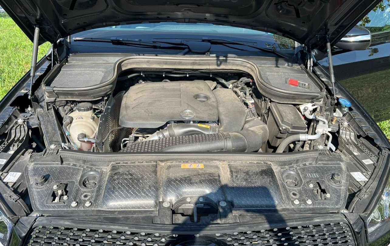 The dirty engine of a black car with the hood open.