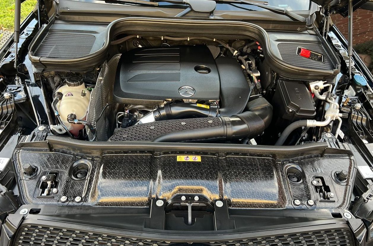 The clean engine of a black car is shown with the hood open.