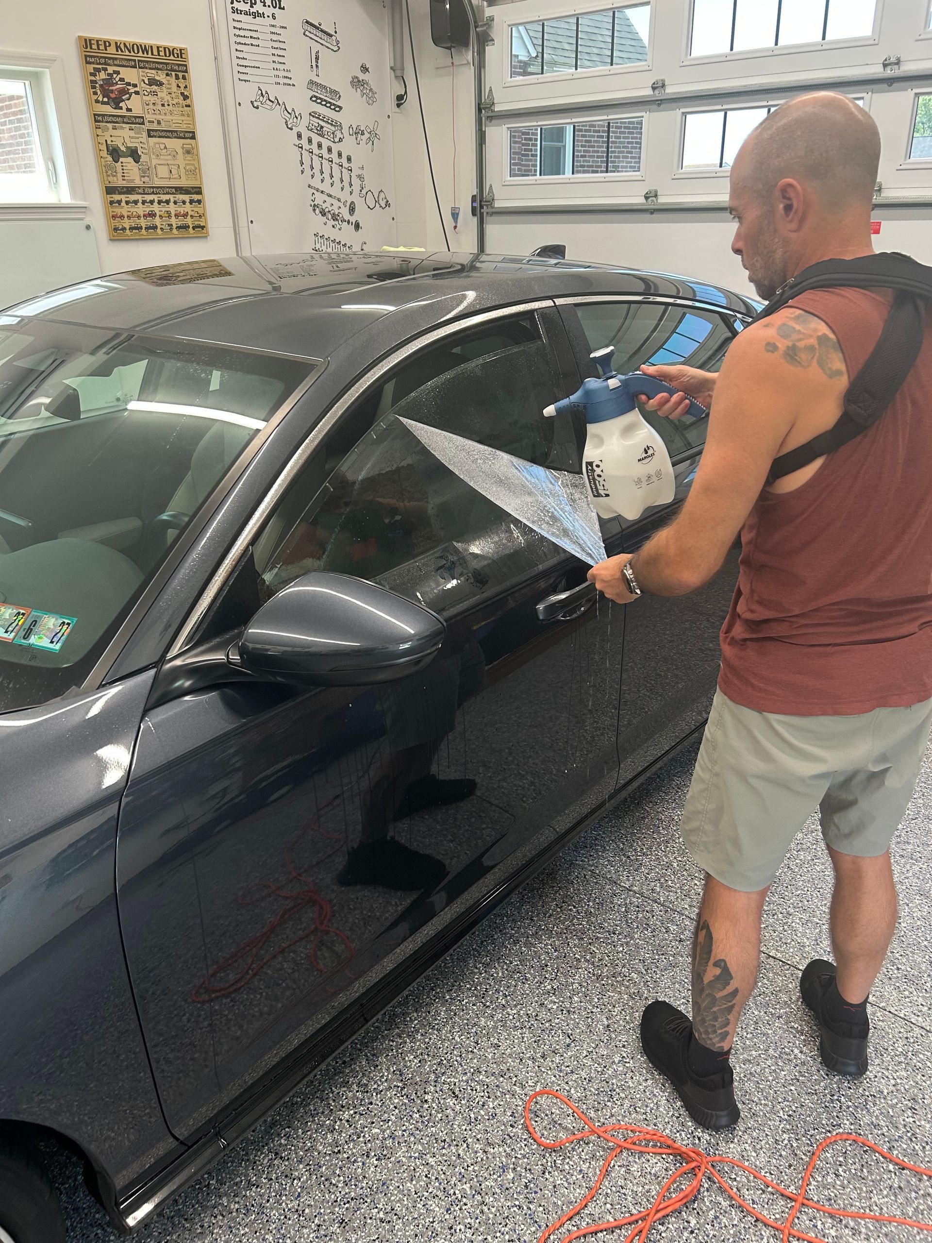 Man using a polishing tool on a black car in a garage