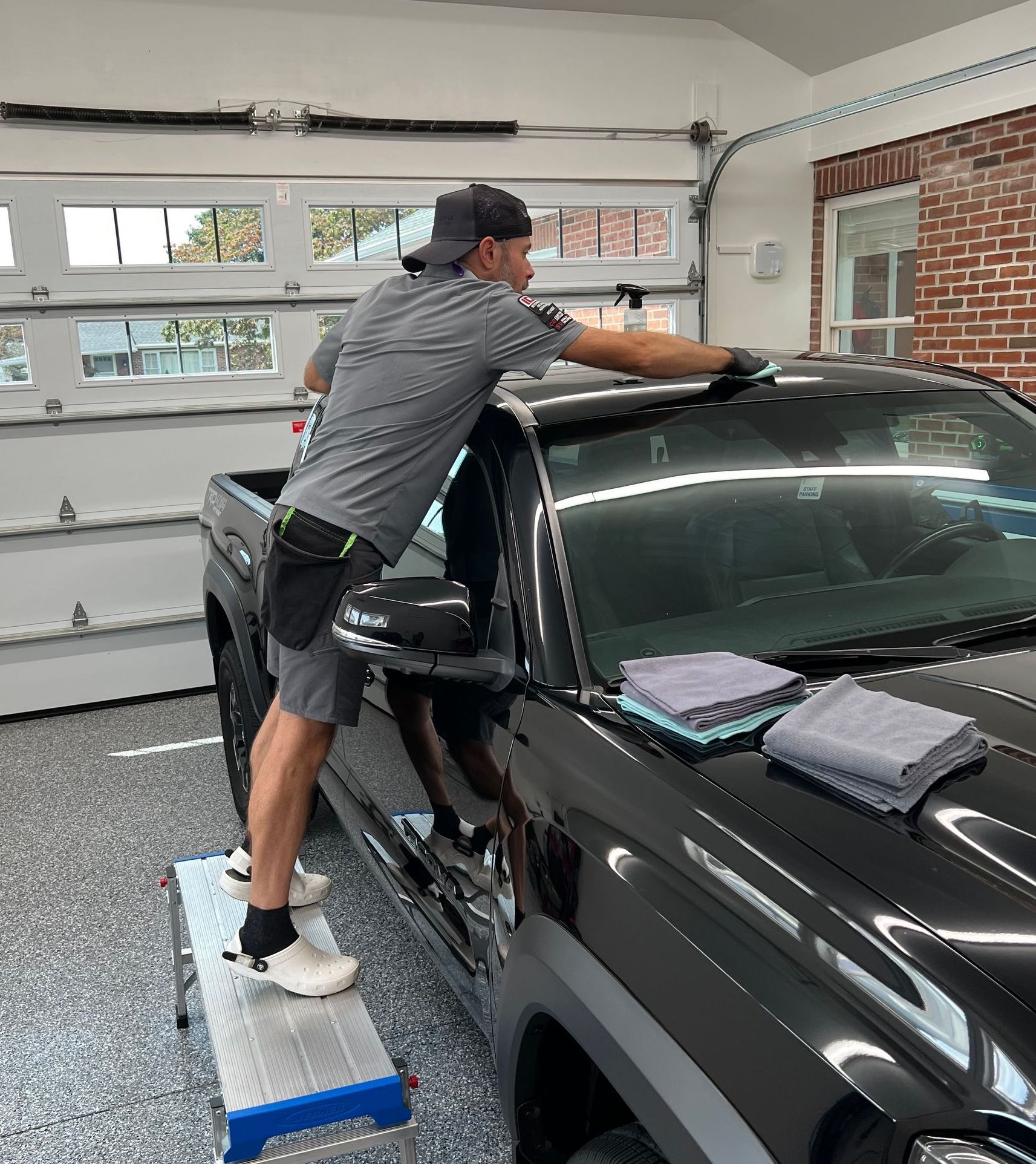 A man is cleaning the windshield of a black car.