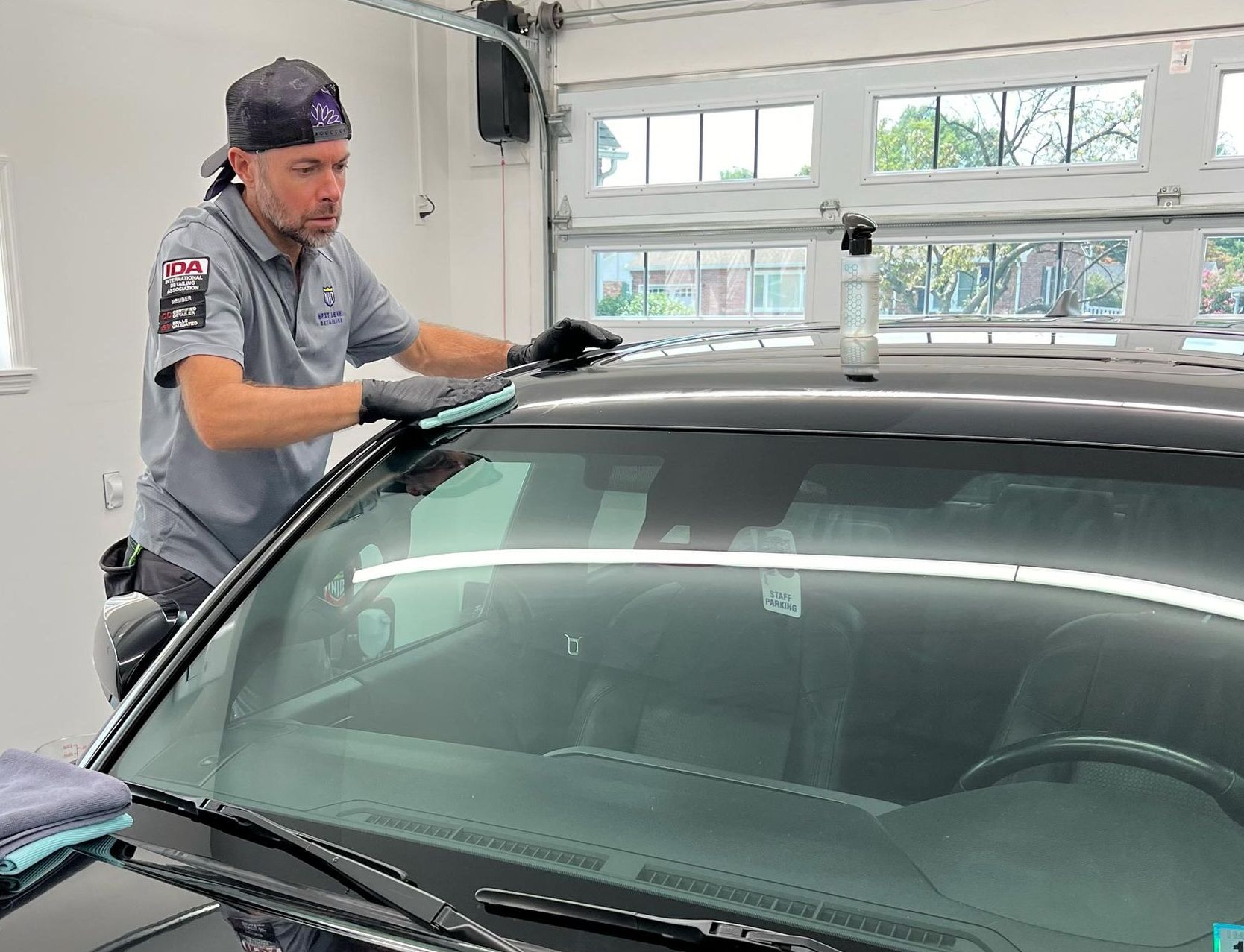 A man is cleaning the windshield of a car in a garage.