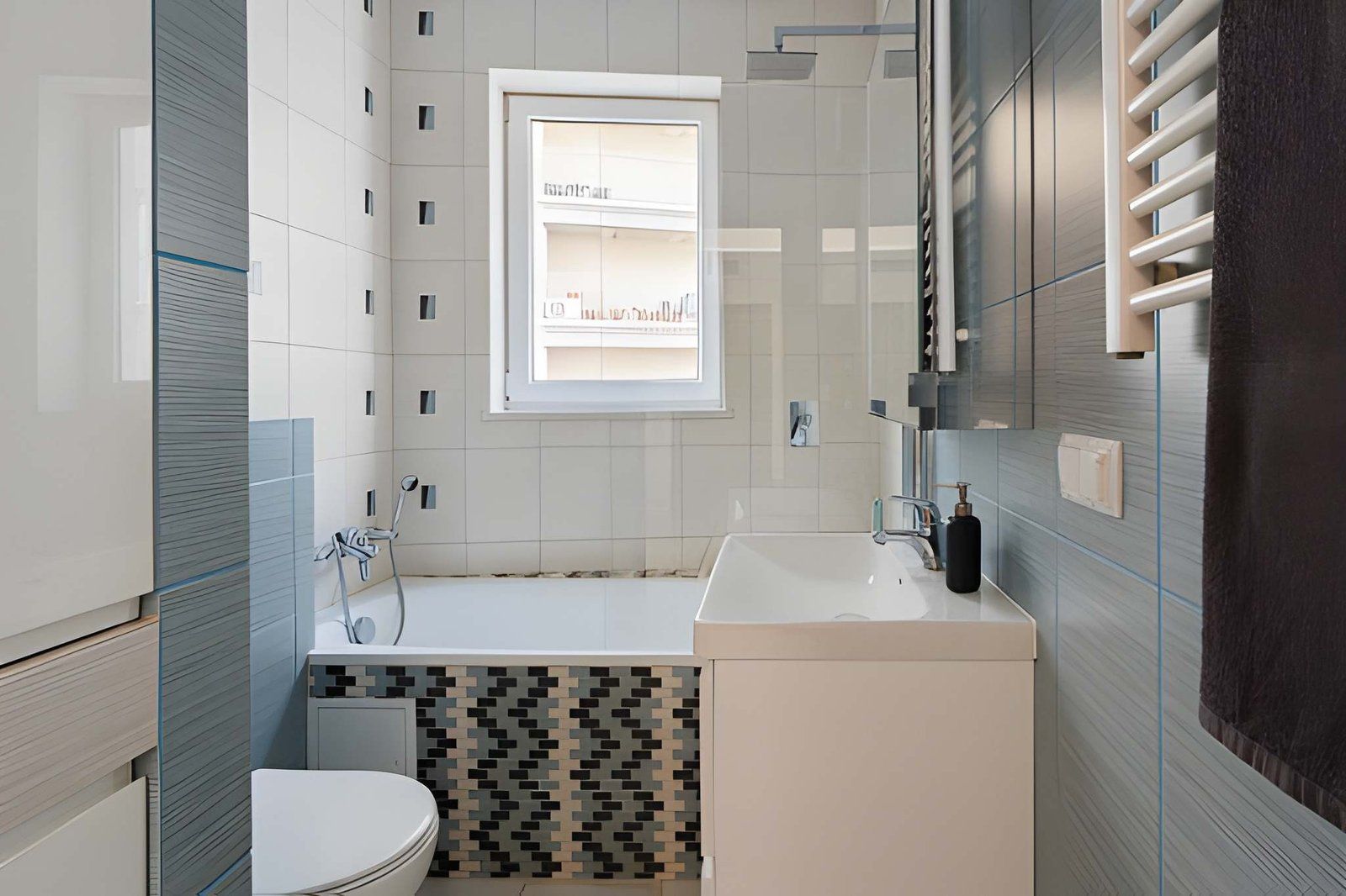 Narrow bathroom with white tiles, bathtub, sink vanity, window, and towel radiator on gray walls