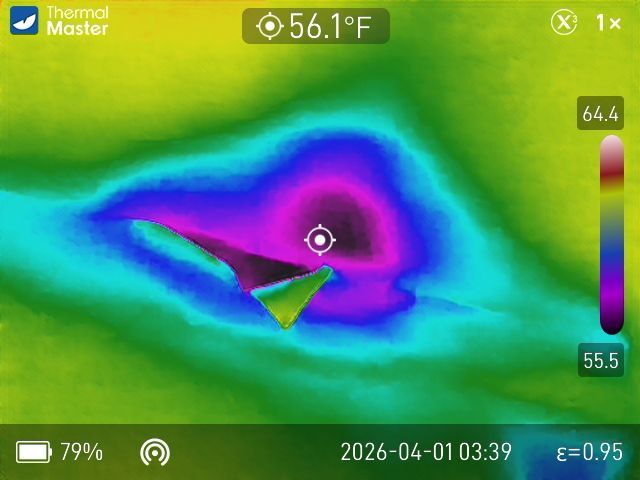 A thermal camera display showing a cool, dark blue and purple center surrounded by warmer green and yellow areas.