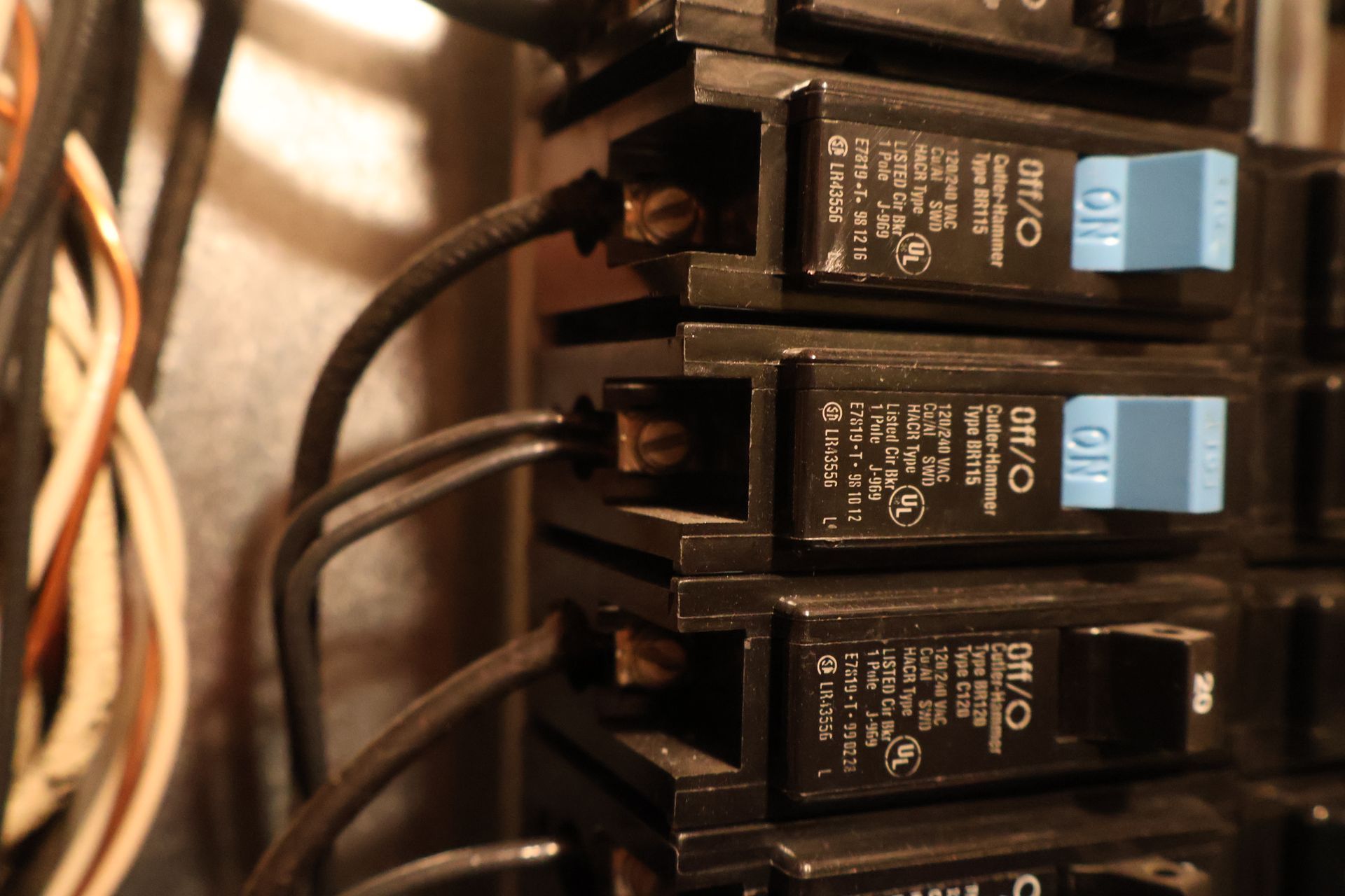 Close-up of a residential electrical panel with several Cutler-Hammer circuit breakers and connected black wires.
