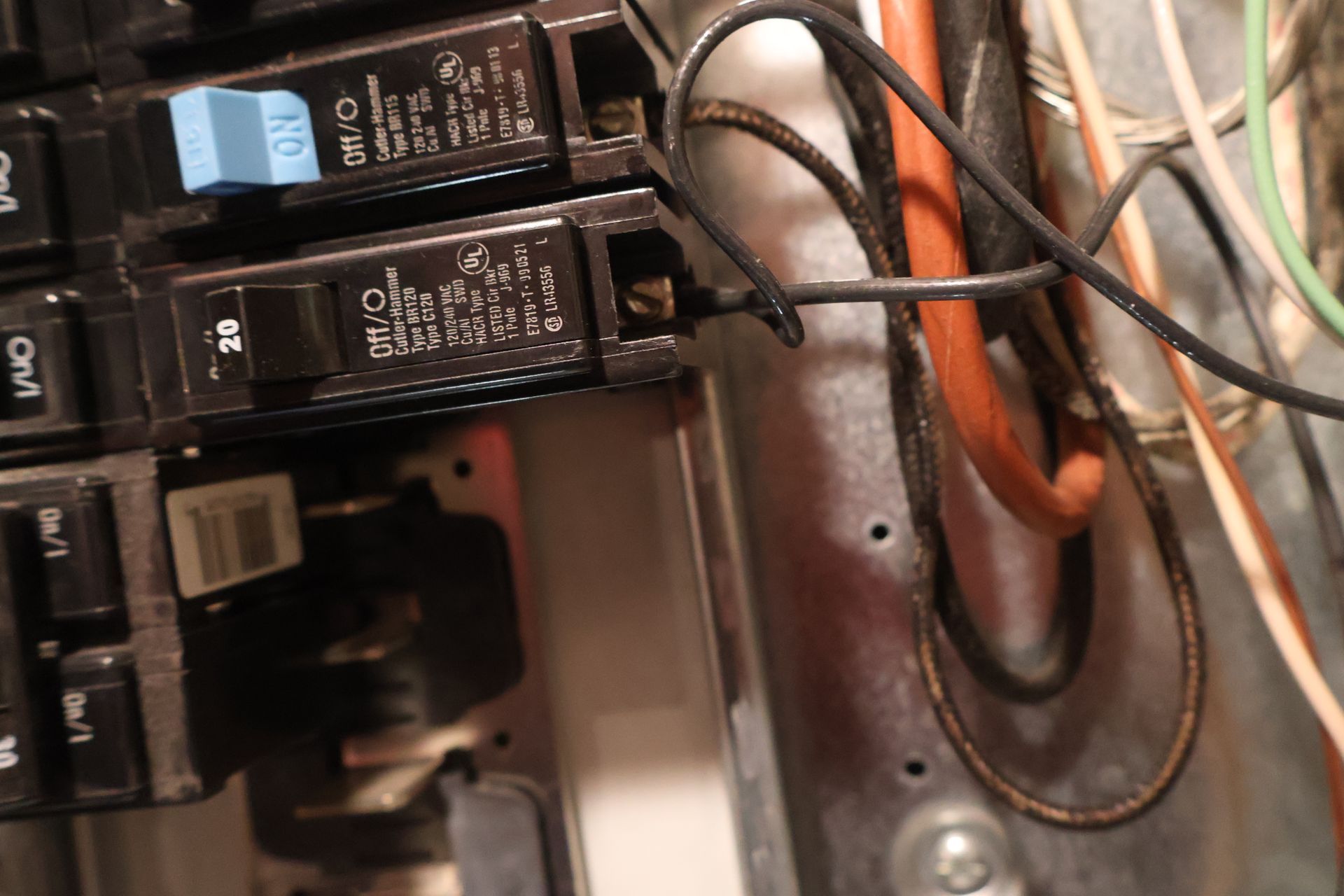 Close-up of a residential electrical panel showing two circuit breakers with black wires connected to their terminals.