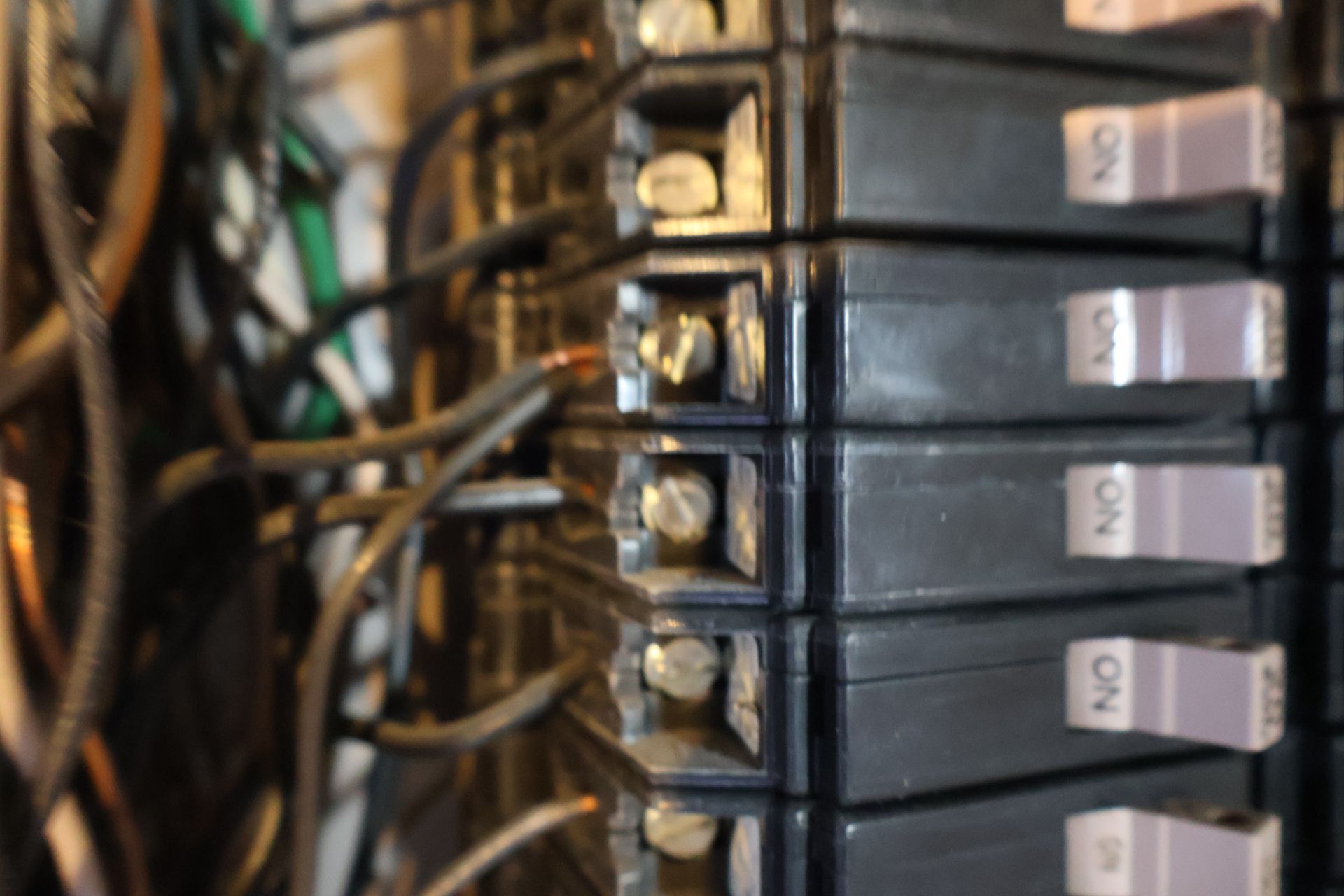 Close-up of the interior of an electrical breaker panel with multiple black circuit breakers and connected wiring.