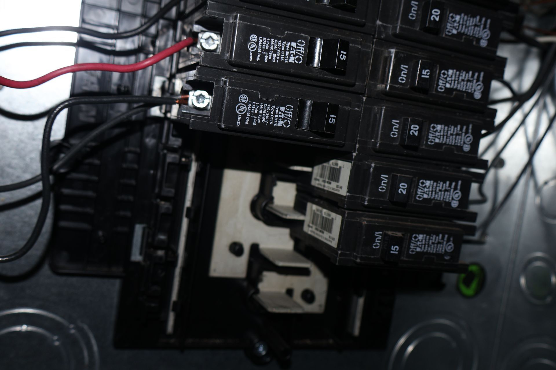 A close-up view of an open electrical service panel showing several black circuit breakers with wires connected to them.