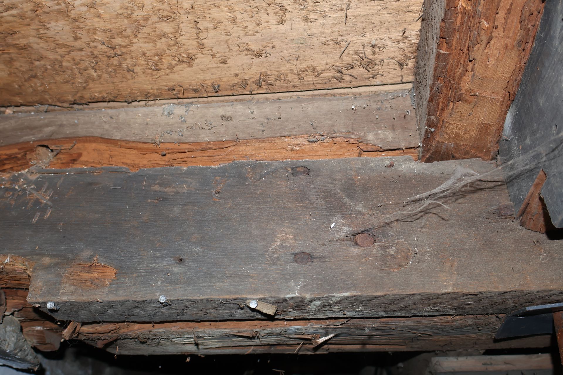 A close-up view of weathered, splintered wooden structural beams showing signs of decay and aging.