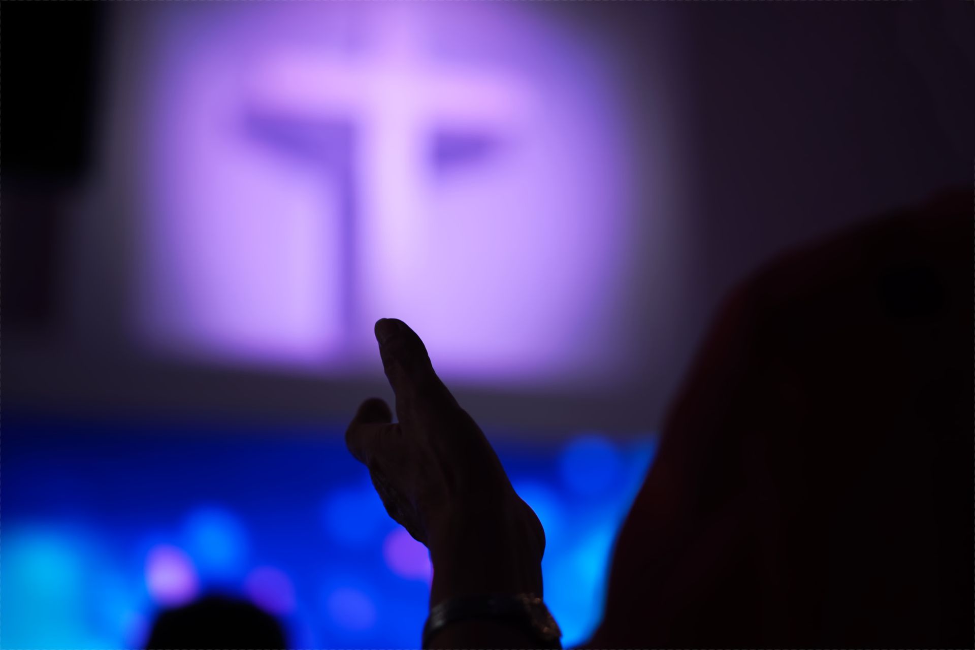 A person is clapping their hands in front of a cross. - Lancaster, TX - International Harvest Fellowship Ministries