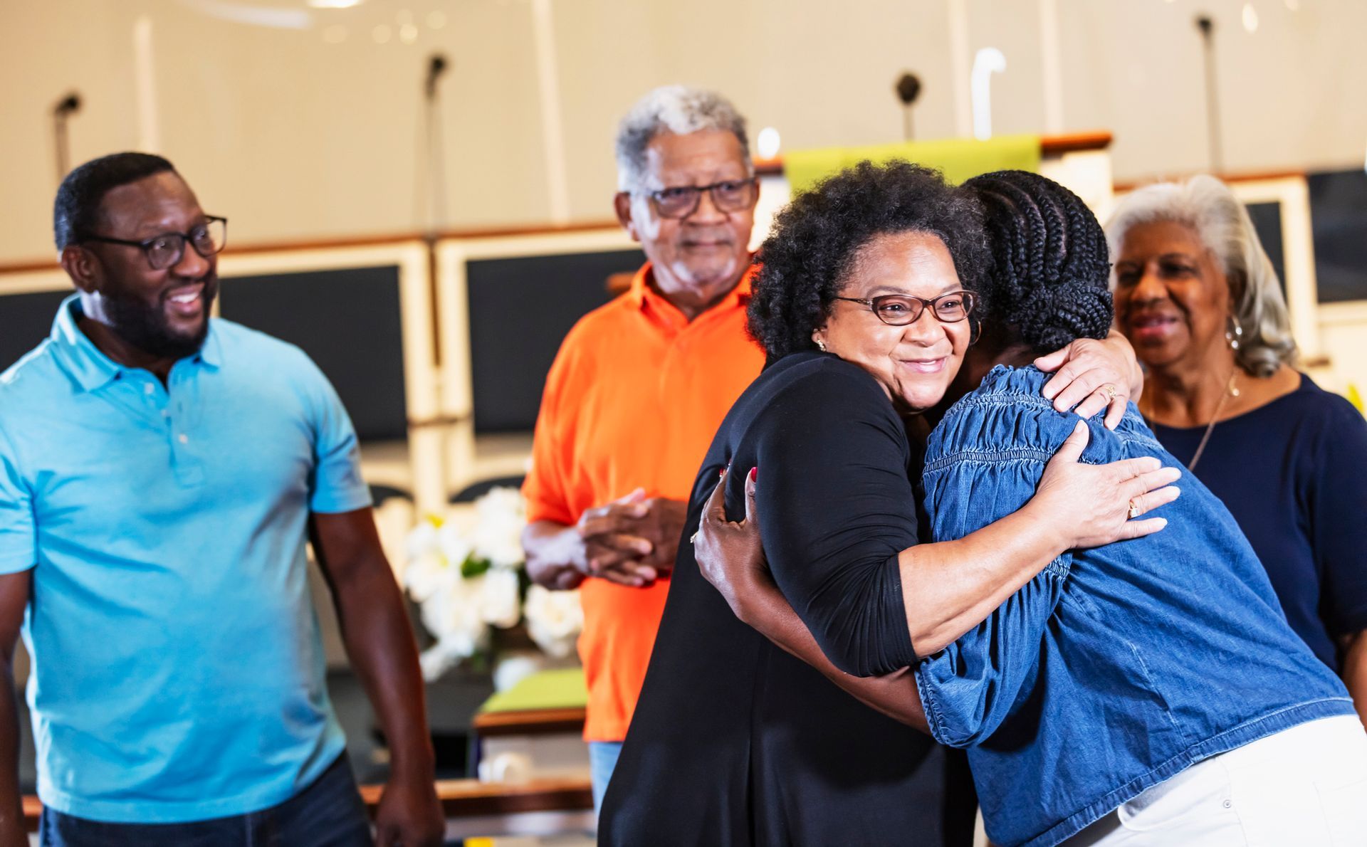 A group of people are hugging each other in a church.