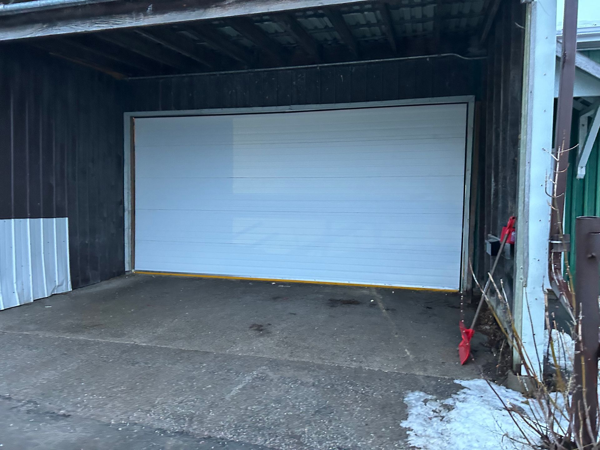 A large white garage door is open in a garage.
