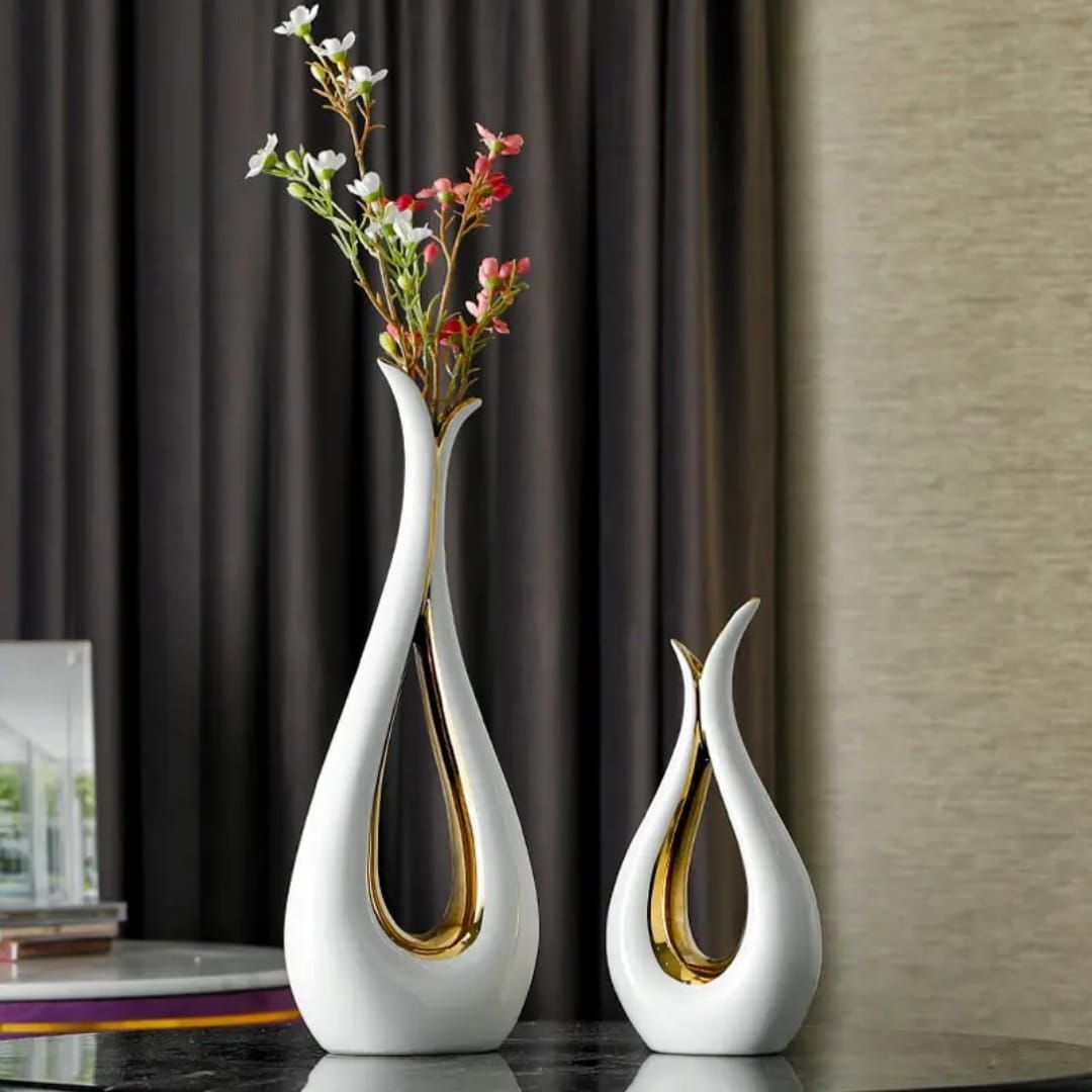 Two white-and-gold decorative vases with flowers on a tabletop