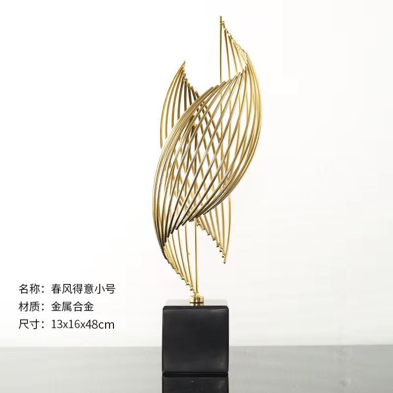 Gold abstract metal trophy sculpture on a black pedestal against a white background.
