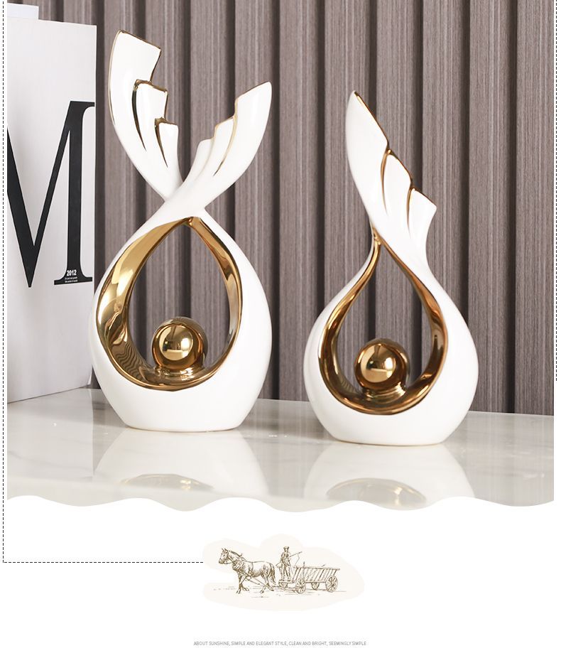 Two white-and-gold abstract decorative sculptures on a shelf against a striped wall