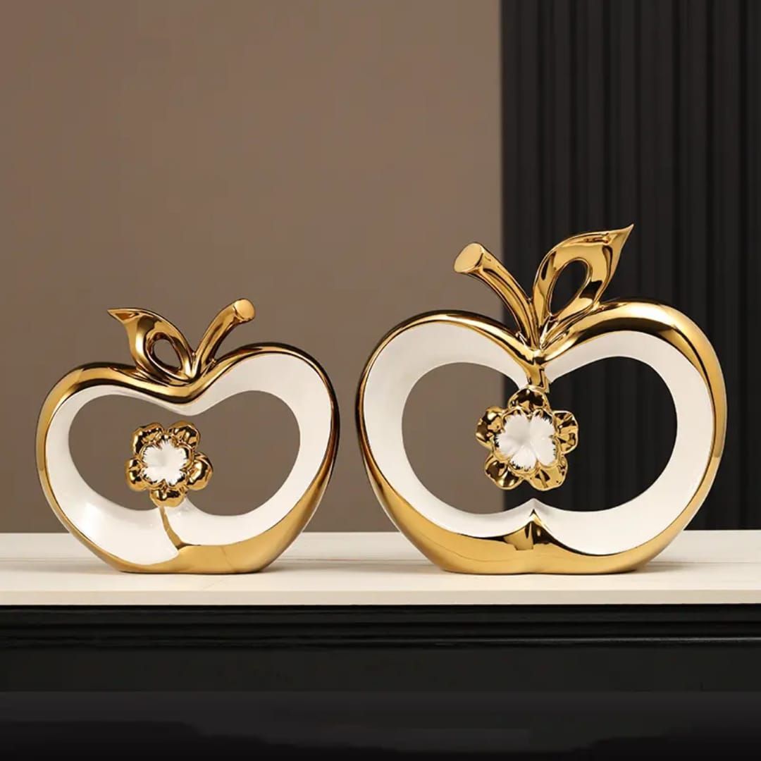 Gold and white apple-shaped ornament with a flower detail on a dark shelf