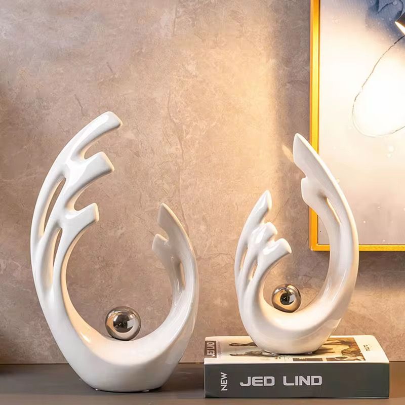 White abstract trophy with a silver ball centerpiece on a small wooden pedestal.