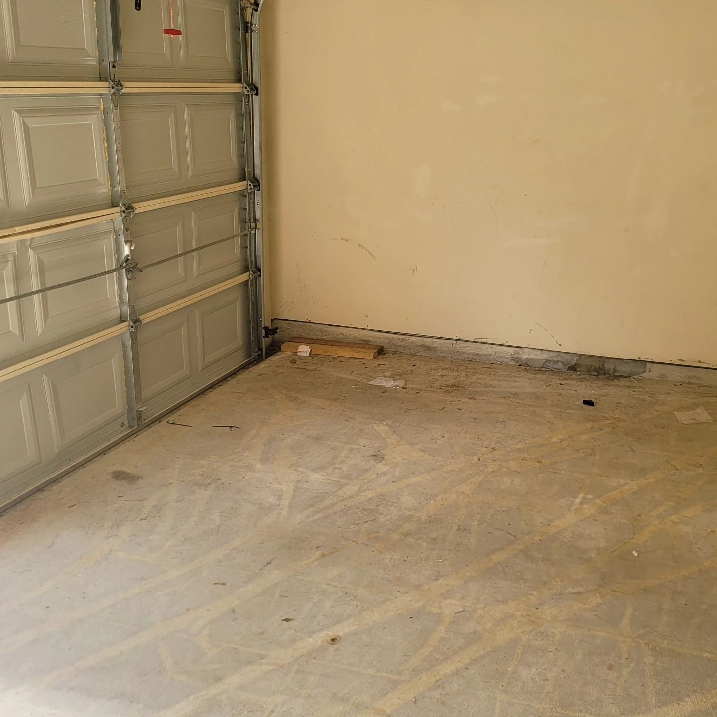Empty garage interior with a concrete floor, closed garage door, and tan walls.