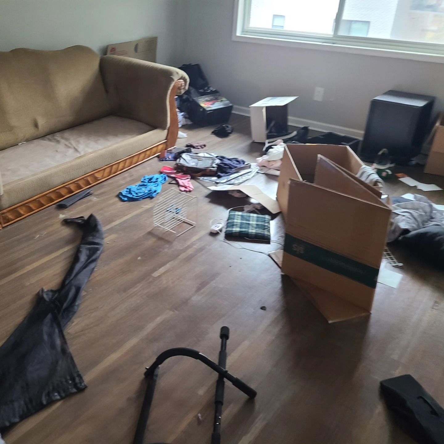 Messy room with boxes, clothing, and a couch.