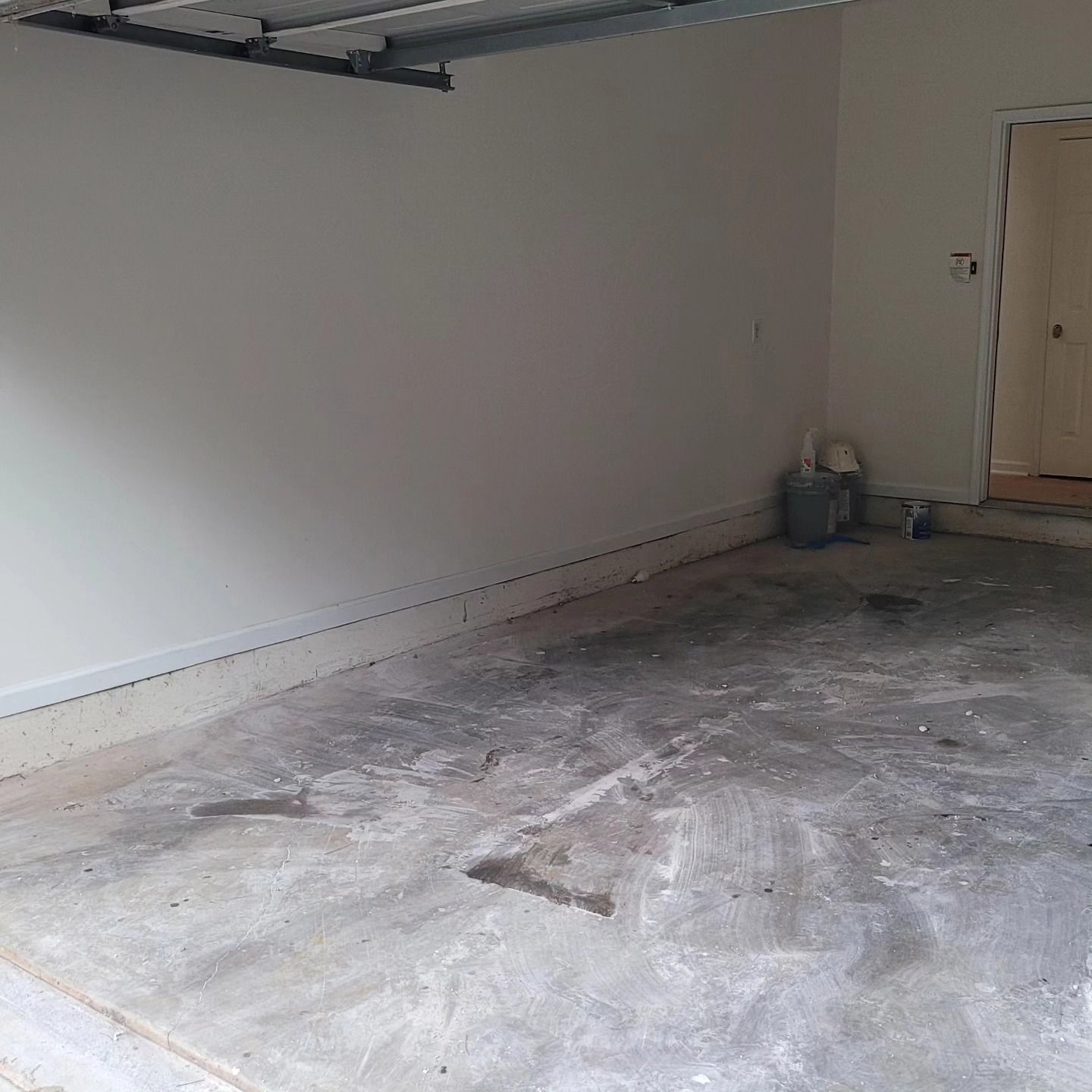 Empty garage with a stained concrete floor and a door in the background.