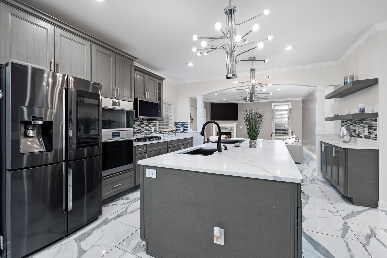 Modern kitchen with gray cabinets, white countertops, and marble tile flooring.