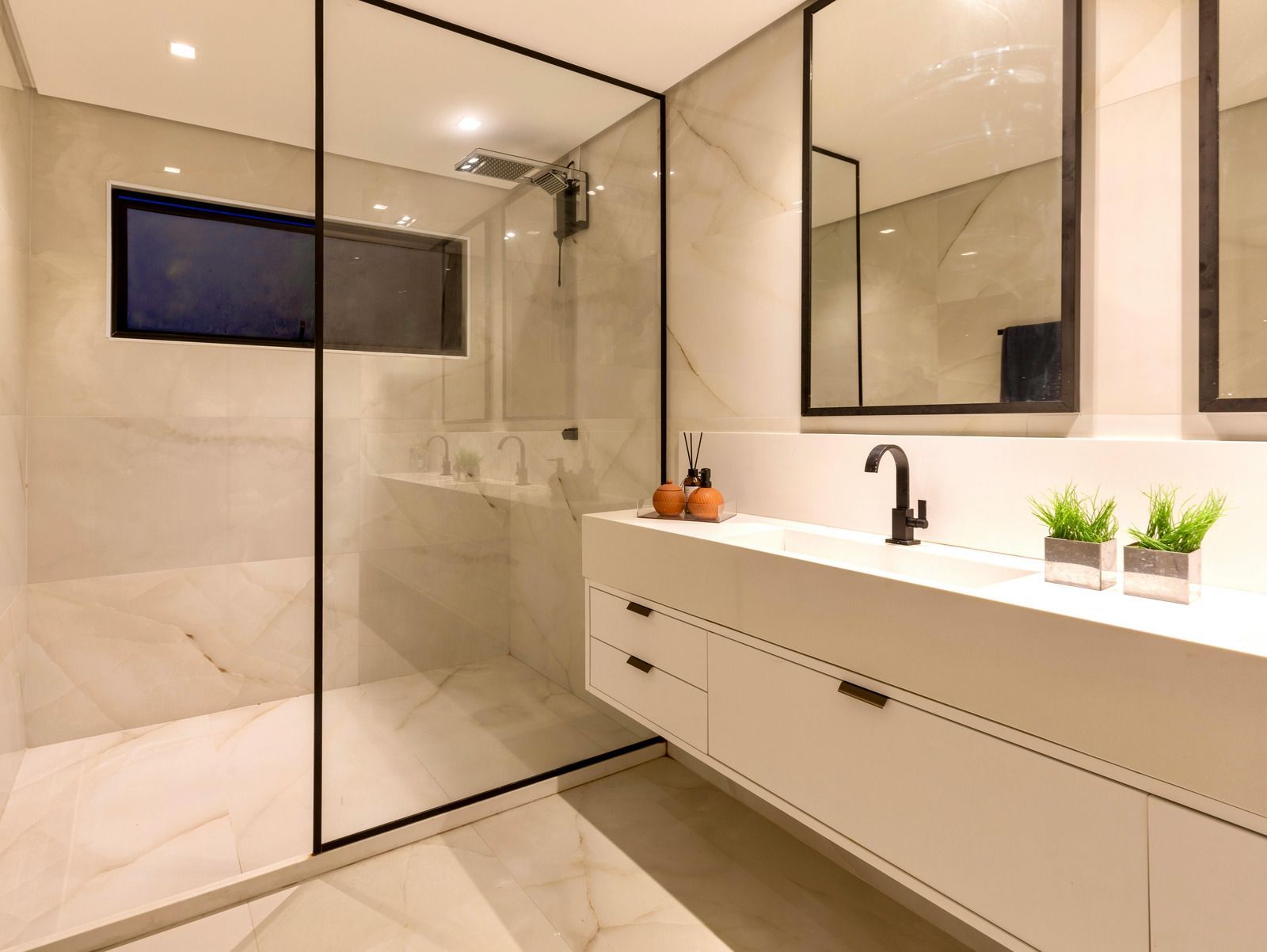 Modern bathroom with a glass shower, white vanity, and marble tile.