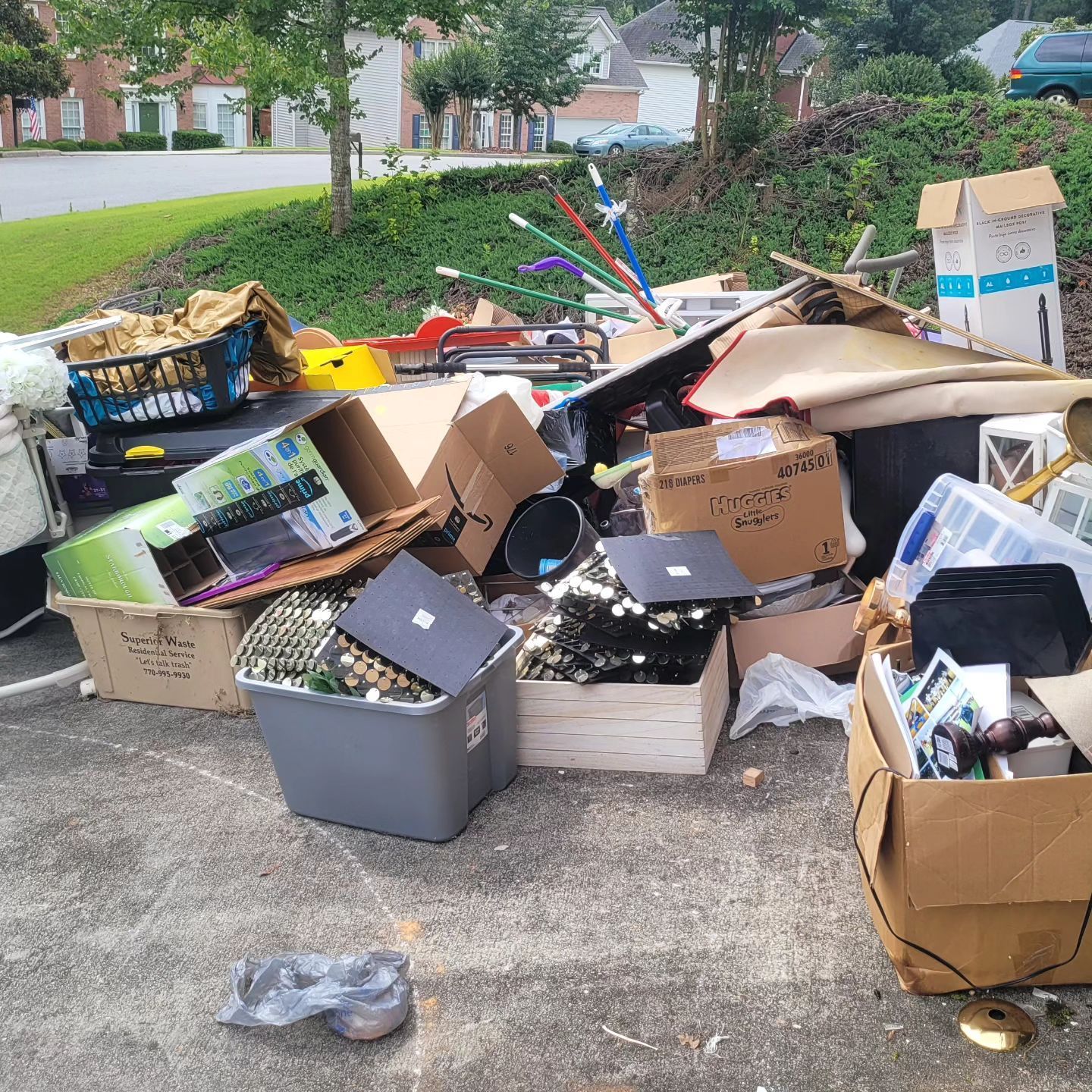 Pile of discarded electronics and household items on a driveway, including boxes and a laptop.
