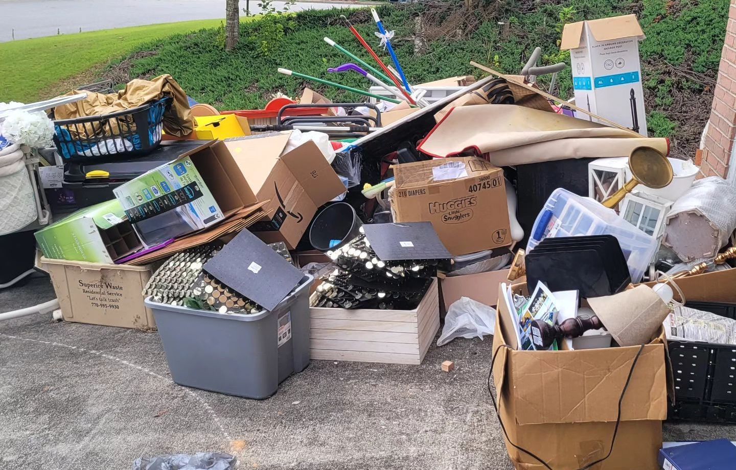 Pile of discarded electronics and household items, including boxes, bins, and a laptop.