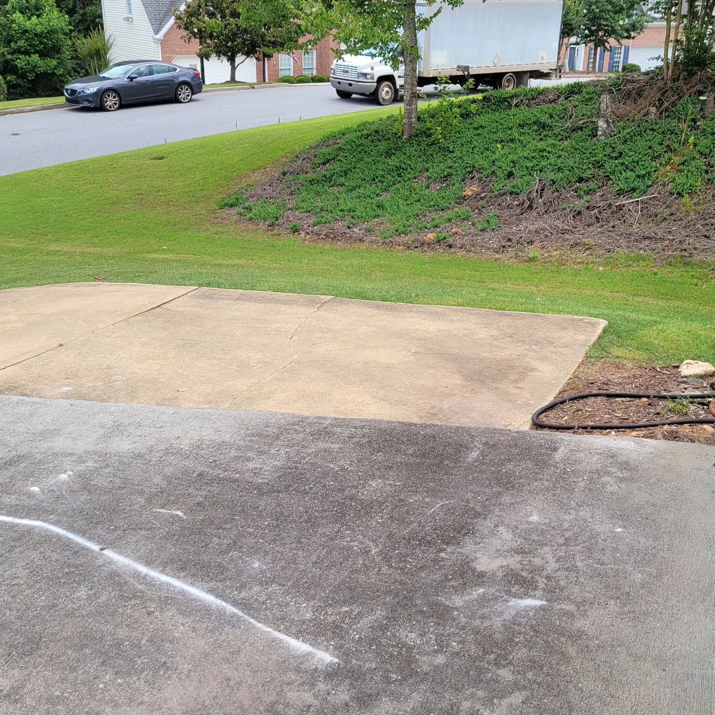 Concrete pad on grass, residential street in background, truck parked on side of road.