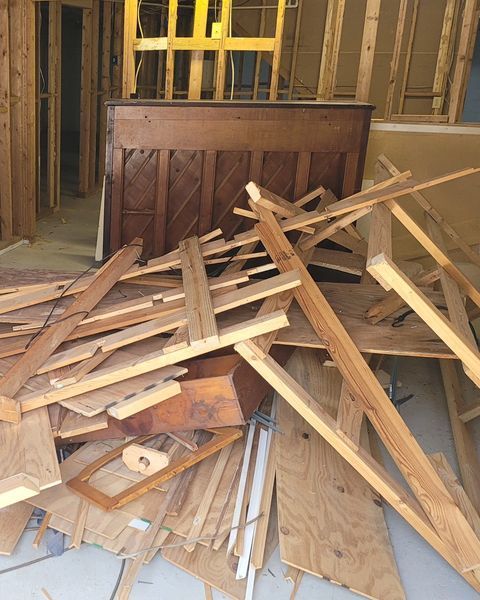 Pile of wood scraps and disassembled headboard inside a building under construction.