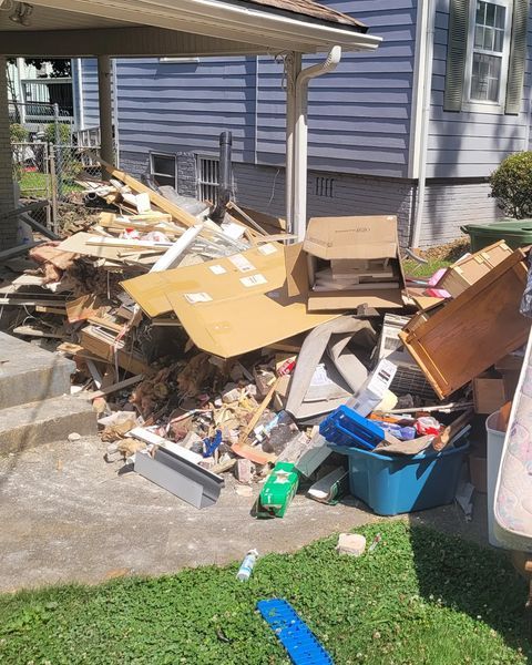 Pile of trash and debris on a porch in front of a house.