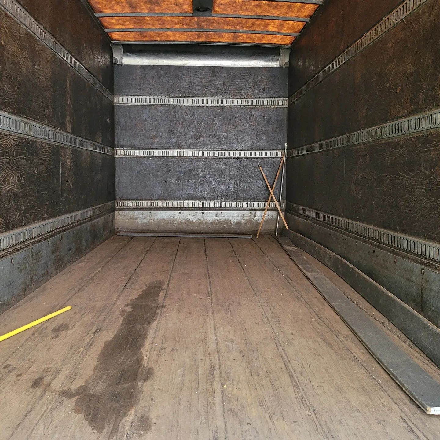 Empty truck trailer interior with wood floor and dark walls.