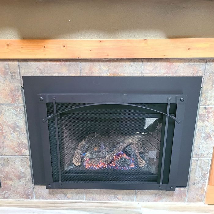 A fireplace with a black screen and a wooden mantle