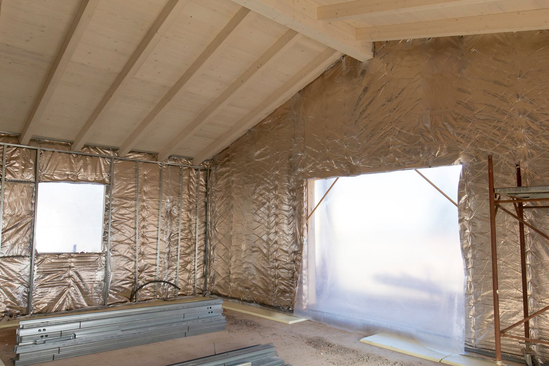 Interior of a building under construction. Walls and ceiling covered in reflective insulation. Unfinished window and floor. Interior of a building under construction. Walls and ceiling covered in reflective insulation. Unfinished window and floor.