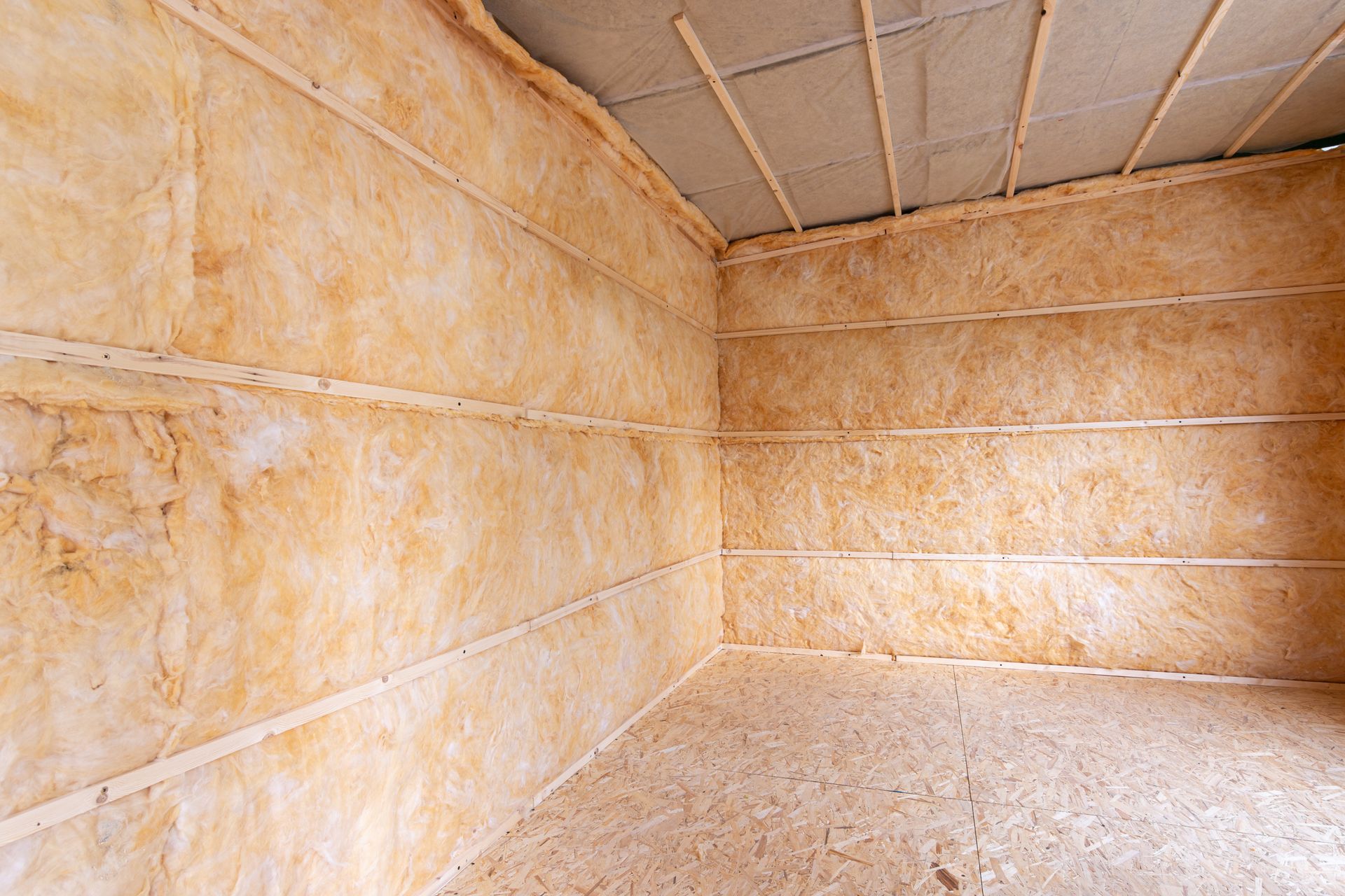 Interior of a room with insulation installed on the walls, and ceiling. Brown and tan colors. Interior of a room with insulation installed on the walls, and ceiling. Brown and tan colors.