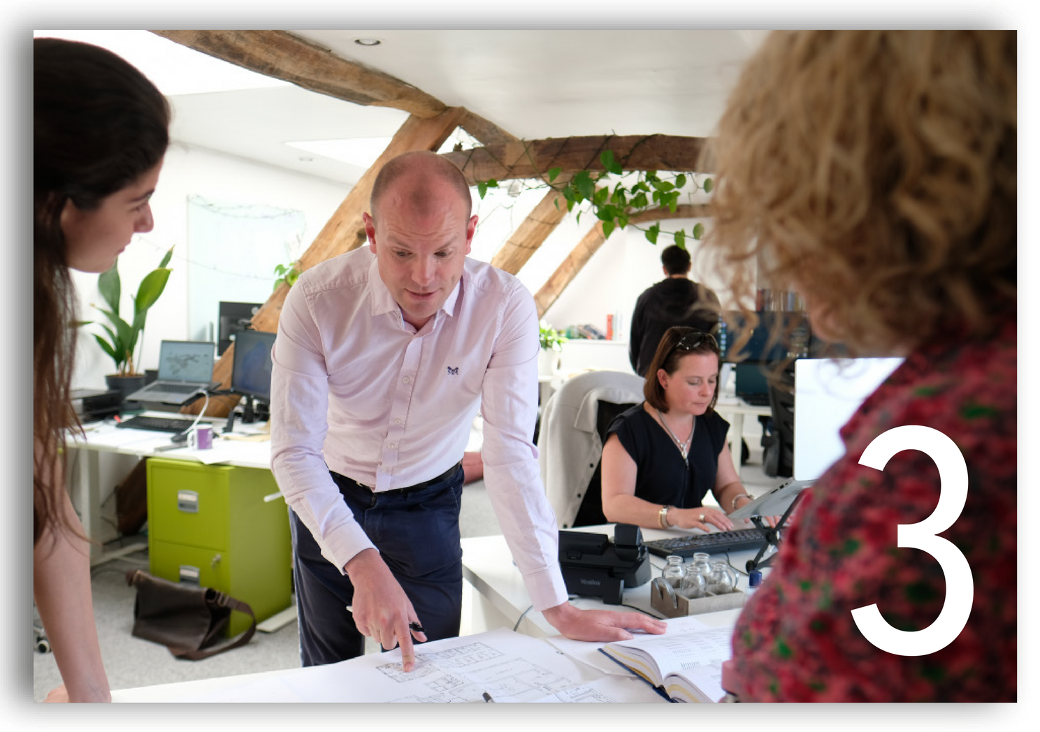 Office team gathered around a table reviewing papers during a meeting