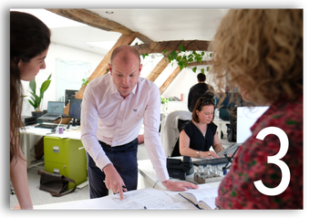 Office team gathered around a table reviewing papers during a meeting