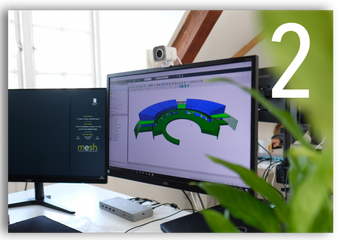 Two monitors on a desk showing a 3D design model, with a plant in the foreground