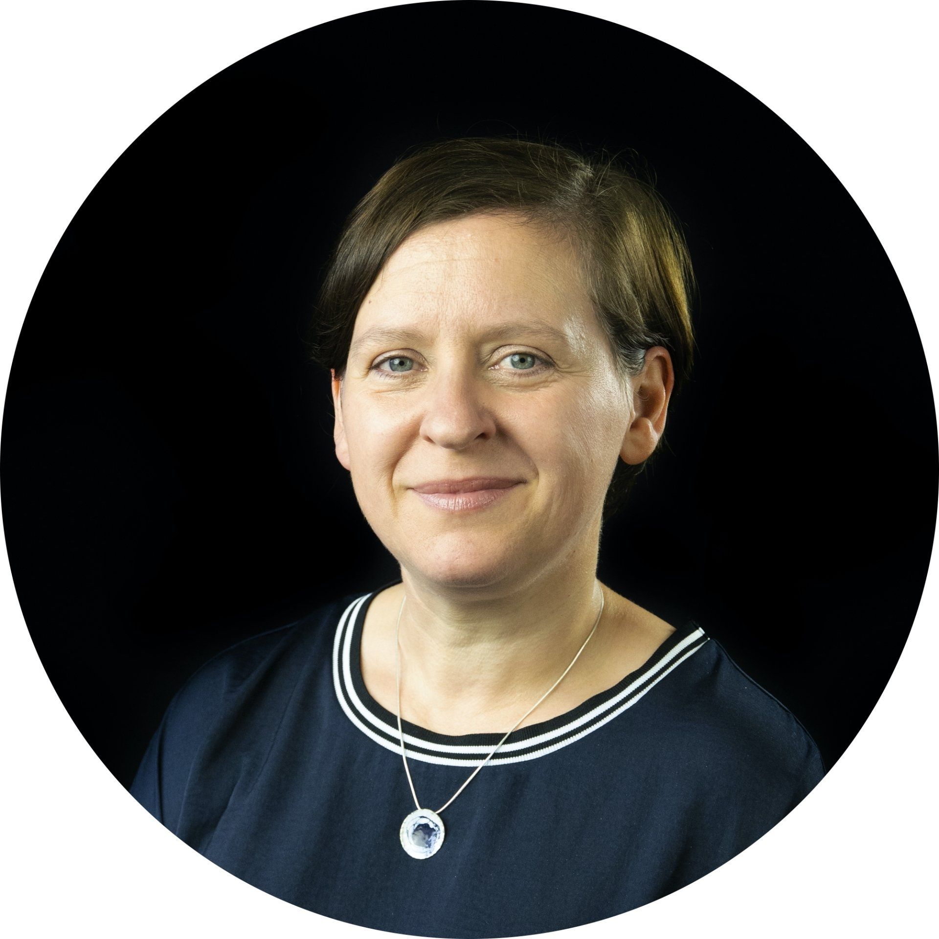 Portrait of a smiling person in a navy top against a black background