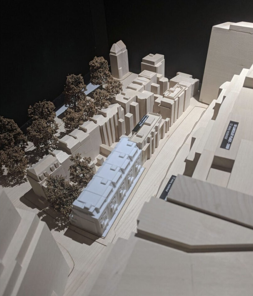 Architectural scale model of a city block with trees and tall buildings viewed from above