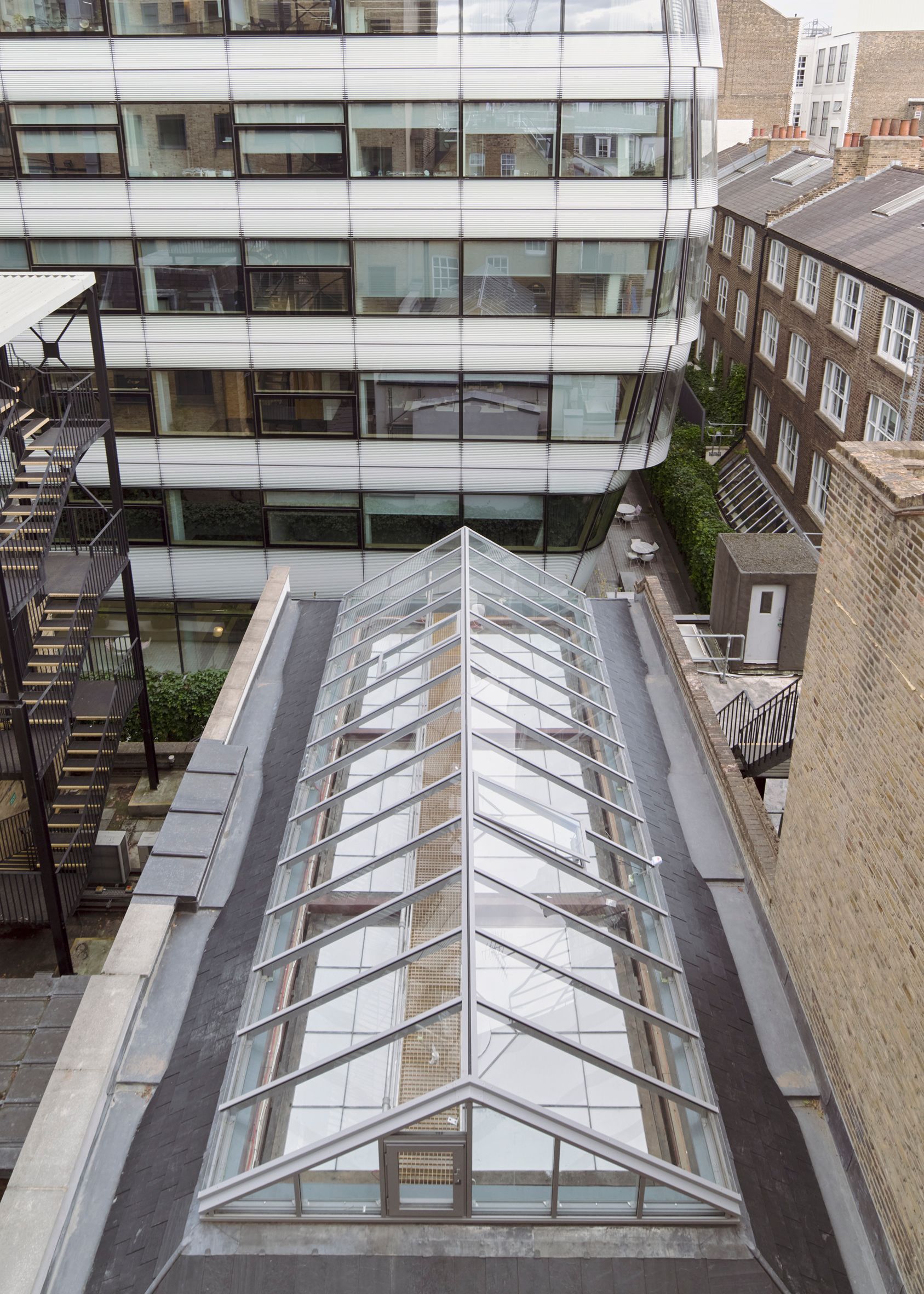 Glass-roofed walkway between modern office buildings in an urban courtyard